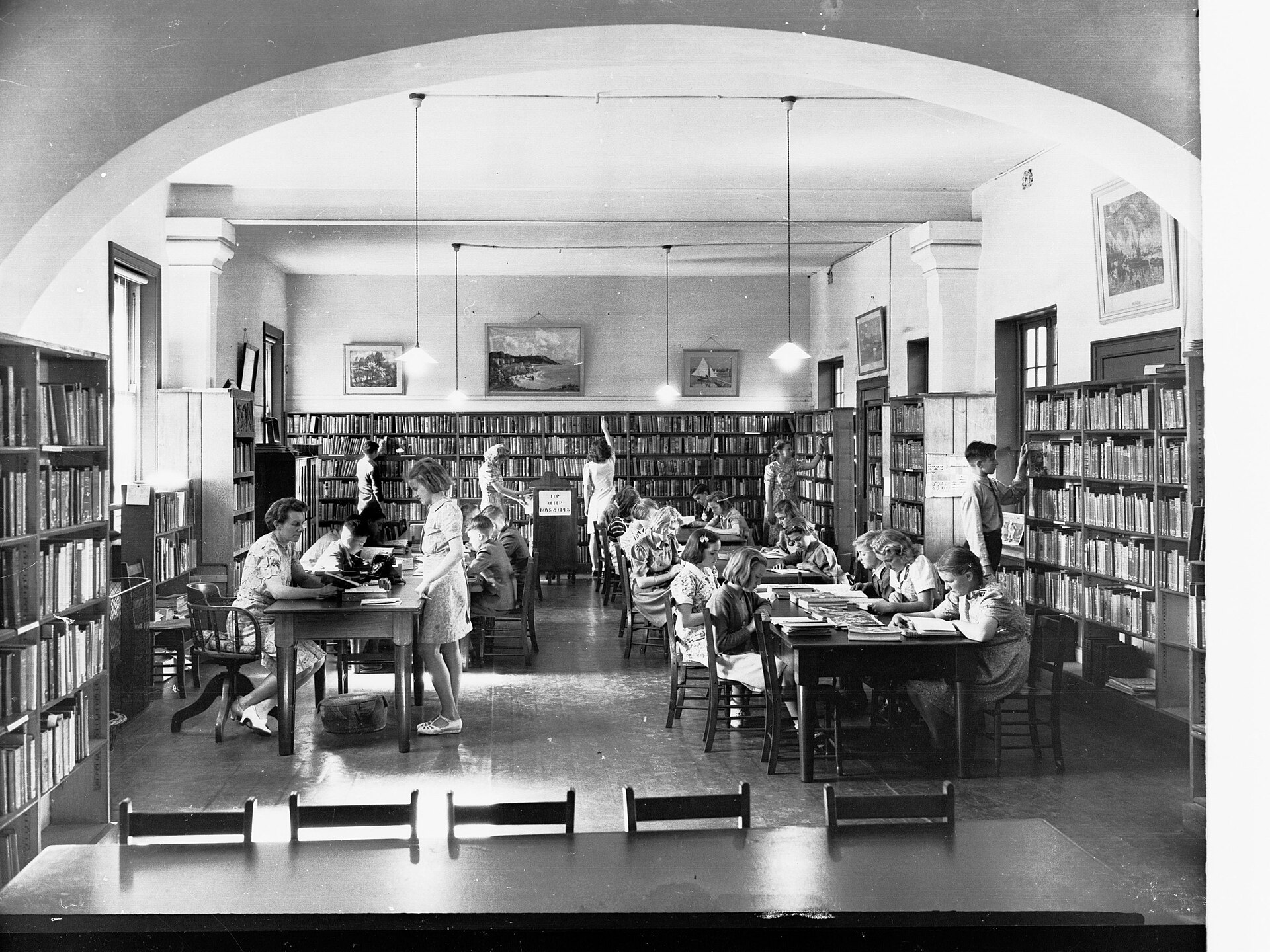 Students reading at tables in a library reading room