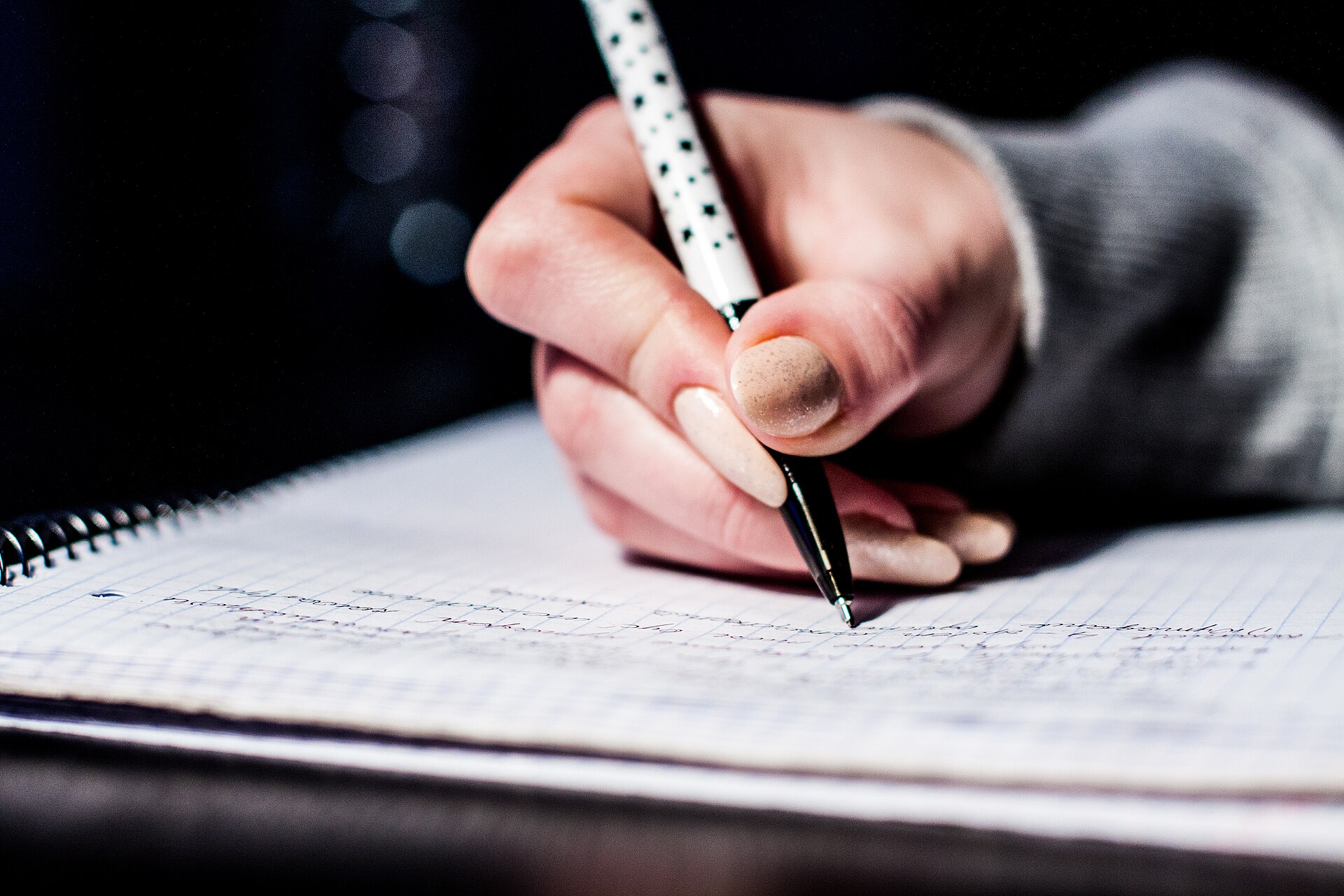 A hand writing notes in a notebook, pen on paper